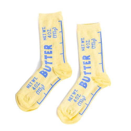 Yellow crew socks designed to look like a butter wrapper with bold blue Butter label and Net Wt 4 oz text by Yellow Owl Workshop