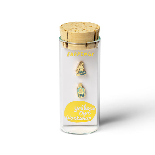 Yellow Owl Workshop mismatched mermaid and message in a bottle stud earrings displayed in signature glass vial packaging with a cork stopper. Gold-tone enamel earrings with blue and teal details, a unique ocean-themed jewelry gift for mermaid lovers and beach enthusiasts.