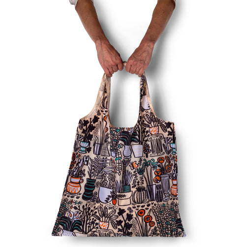 Person holding a patterned tote bag against a white background