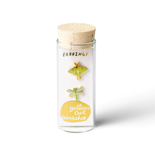 Glass bottle with wooden cap containing earrings on a white background
