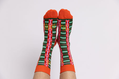 Red and green plaid So Freaking Merry crew socks worn on leg straight on by Yellow Owl Workshop