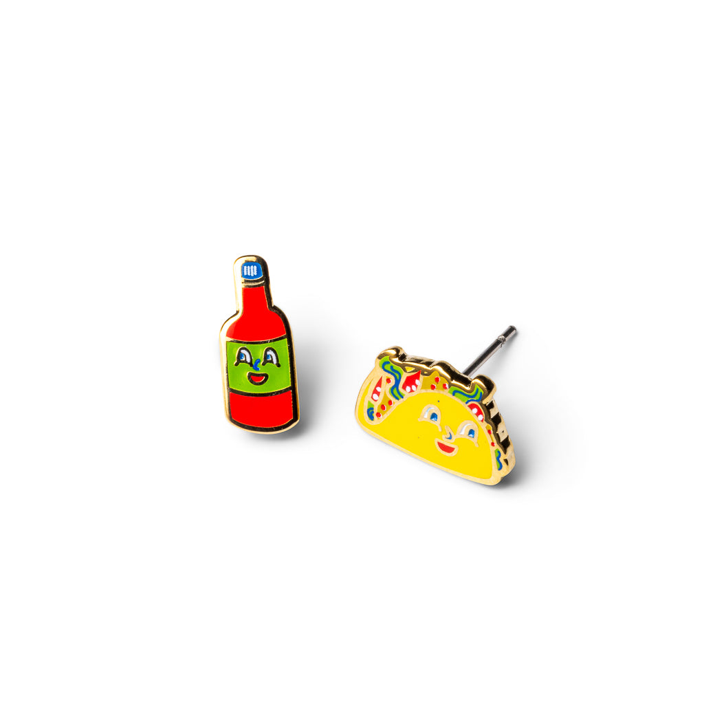 Mismatched gold stud earrings featuring smiling hot sauce bottle and smiling taco with cartoon faces by Yellow Owl Workshop