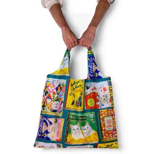 Person holding illustrated funny tote bag with vintage useless book cover print by Anna Hoyle for Yellow Owl Workshop
