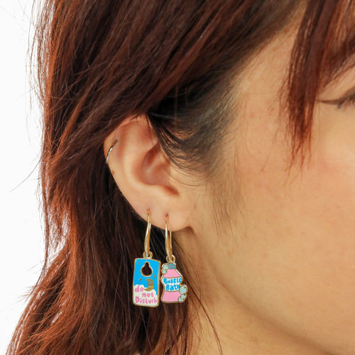 Self Care Bubble Bath mismatched enamel drop earrings worn on ear by Yellow Owl Workshop
