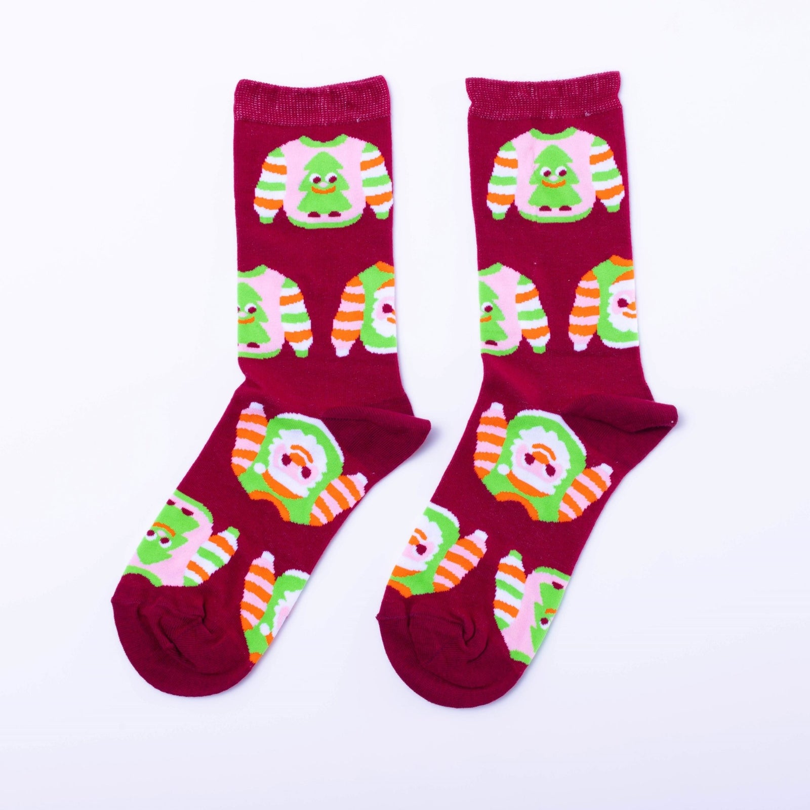 Red crew socks featuring illustrated ugly Christmas sweaters with Christmas trees and orange green stripes by Yellow Owl Workshop