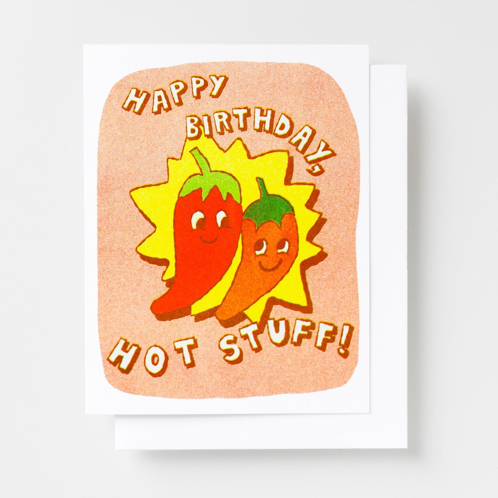 Risograph greeting card with two smiling chili pepper characters on a yellow starburst and peach background, text reads Happy Birthday Hot Stuff in bold orange lettering